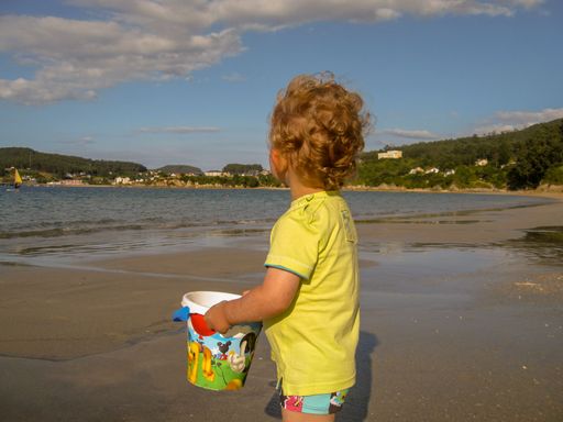 A two year old son having a good time in a beach in the Cantabrian sea