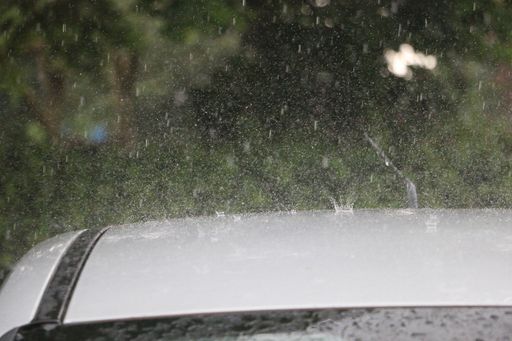 A closeup shot of raindrops falling on a car roof