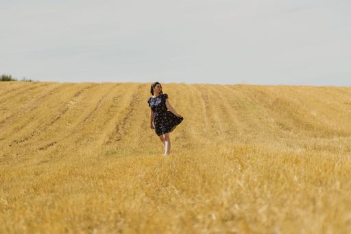 A beautiful shot of a female walking in the middle of yellow fields in Rio de Onor, Braganca, Portugal