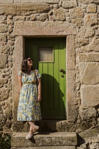 A young female standing near a green door of an ancient building