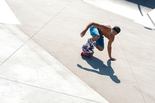 A high angle shot of a skateboarder doing tricks on his skateboard during a sunny day