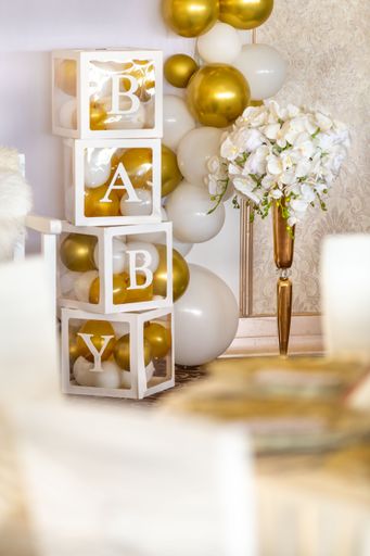 A vertical shot baby gender reveal party decorations with boxes with white and gold balloons