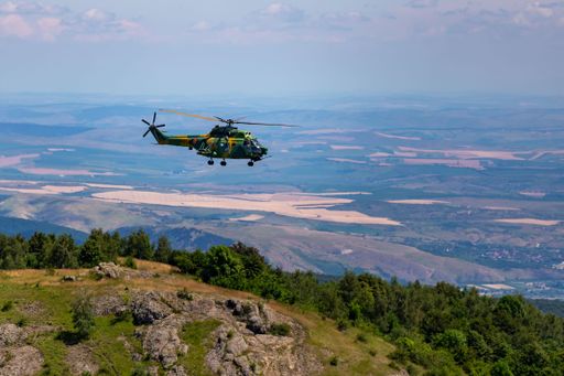 A IAR 330 Aircraft model helicopter flying in the sky over green mountains and vegetation