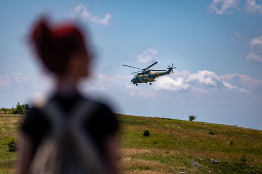 A blur girl looking at IAR 330 Aircraft model helicopter flying in the sky over green plains