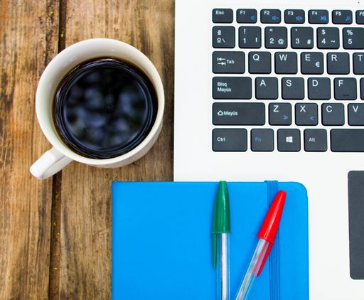 A top view shot of copybook with pencils, laptop and a cup of coffee