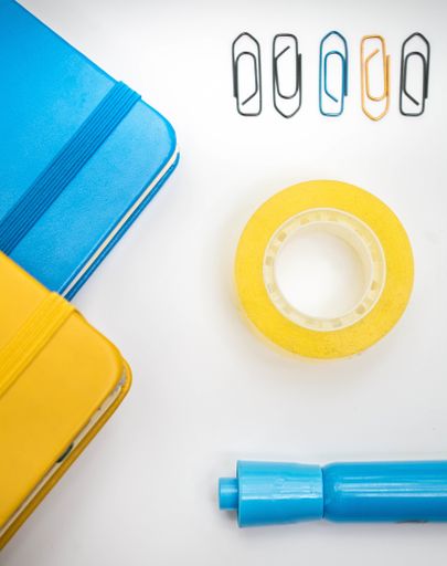 A top view shot of multicolored copybooks, clips, marker and duct tape isolated on white background