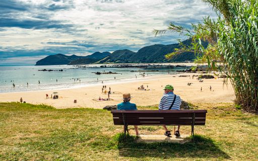 The aged people sitting on a bench on the coast of the sea