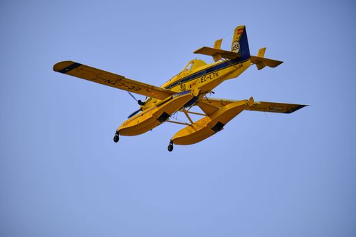 A yellow hydroplane flying in clear blue skies