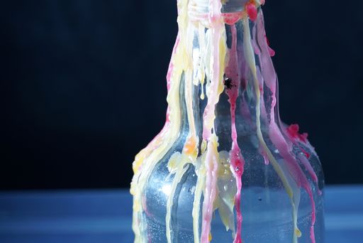 A closeup shot of a plastic bottle with a melted candle wax