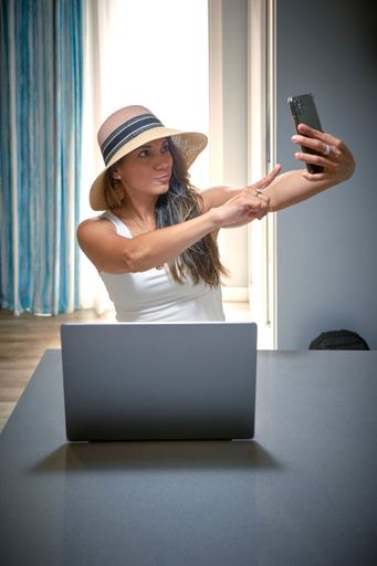 A vertical shot of a business woman posing and taking a selfie with her phone