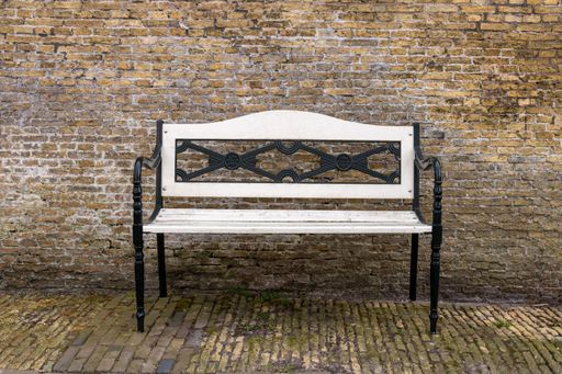 Park bench on a concrete stone backdrop. black and white bench.