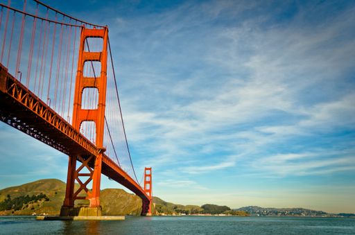 A low angle shot of the golden gate bridge with a blue cloudy sky in the background at daytime