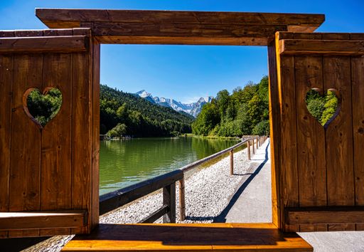 The view through a wooden window to a lake in the Alps mountains in Southern Germany