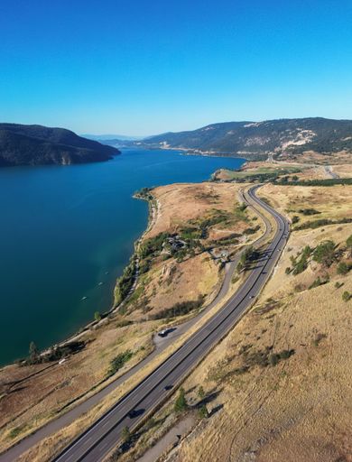 Scenic Highway in the desert by the lake. Aerial View. Sunny Summer. Near Vernon, British Columbia, Canada.
