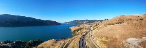 Scenic Highway in the desert by the lake. Aerial View. Sunny Summer. Near Vernon, British Columbia, Canada. Panorama