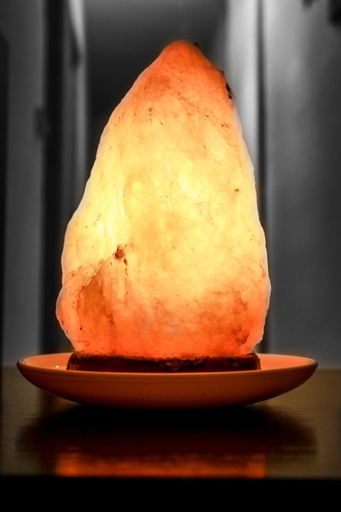 A vertical shot of an illuminated salt lamp in the dark