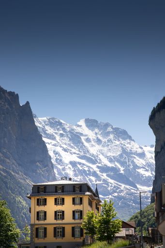 A vertical shot of a building with snowy mountains in the background
