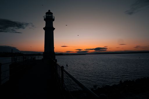 A beautiful sunset over the sea with a silhouette of a lighthouse