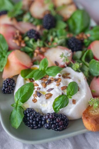 A vertical shot of blueberry salad with vegetables and feta cheese on a plate