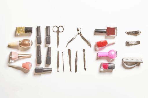 A top view of stylish trendy manicure accessories with gel nail polishes, and scissors on the white background