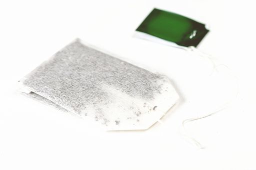 A tea bag with a blank green tag isolated on white background