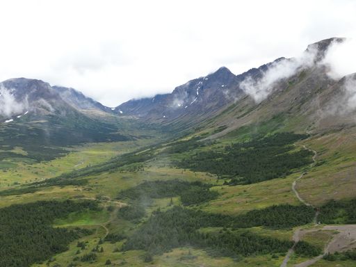 A mesmerizing view of green hill with a white cloud over and on it