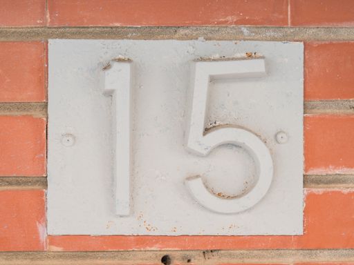 The fifteen house number placed on the brick wall.