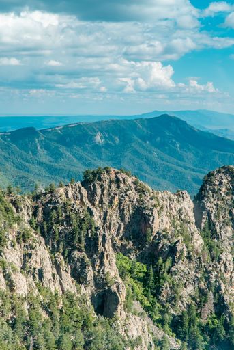 A vertical shot of the cliffs covered with green vegetation. View from Sandia Peak. Albuquerque, USA.