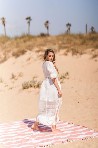 A vertical shot of a pretty lady standing on a towel on a sandy beach
