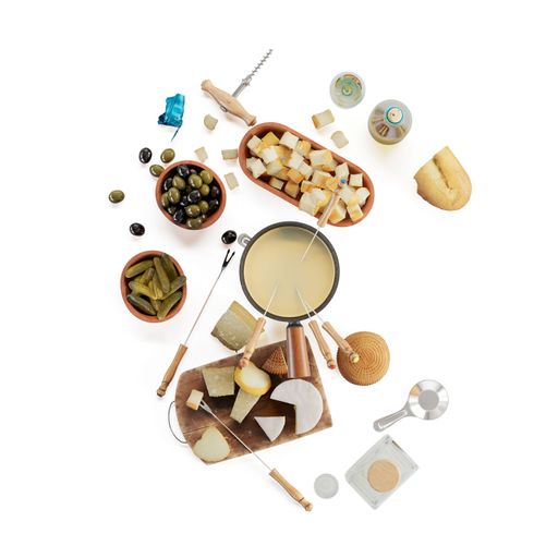 A closeup of a cheese platter, fondue, alcohol bottles, pickles and olives on a white background