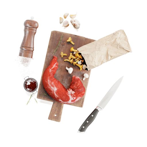 A closeup of a raw pork tenderloin with mushrooms on a wooden board next to utensils and garlic cloves