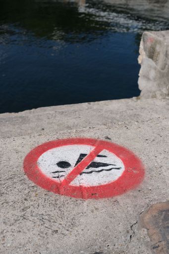 A vertical shot of a no swimming sign painted on the floor of a pier in Paris, France
