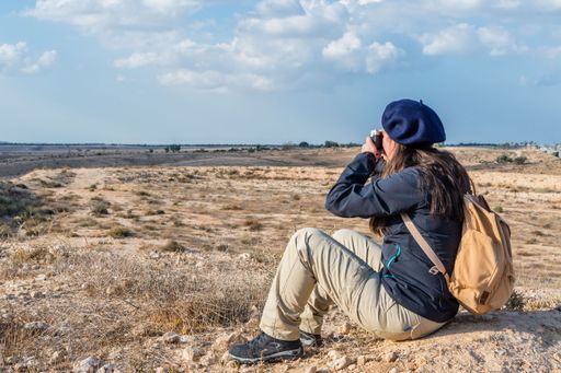 A pretty young woman with a blue beret hat photographing with a camera in the deserted valley