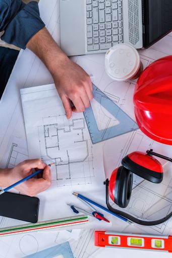 A top view of an engineer at the office desk designing a construction project.