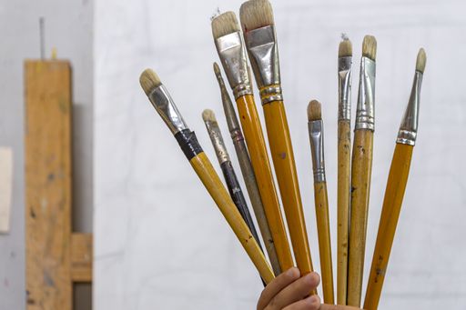 Art brushes for painting in the hands of a child on a white canvas background