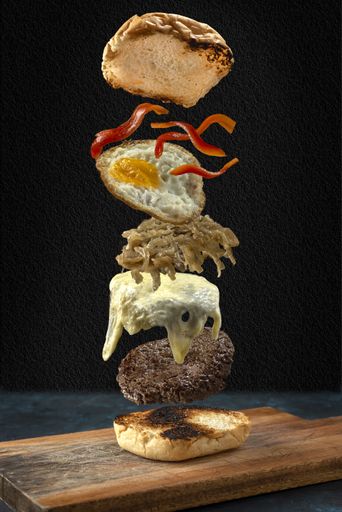 A vertical shot of a delicious burger with onions, egg, cheese and pepper
