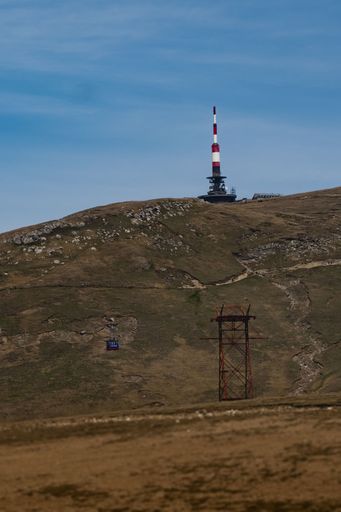 A tower on top of the hill with a cloudy blue sky