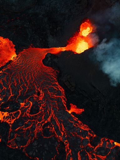 A vertical shot of lava flowing over rocky surface during 2022 Meradalir volcano eruption, Iceland