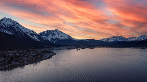 A breathtaking view of the lake surrounded by snowy mountains during scenic sunset in Seward, Alaska