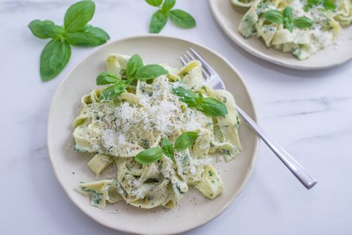 A top view of Italian pasta Cheese and Pepper (Cacio e Pepe) served with basil leaves on white background