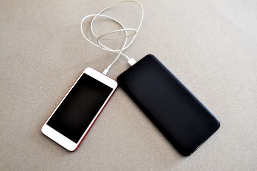 A closeup shot of a smartphone connected to a power bank on a gray surface