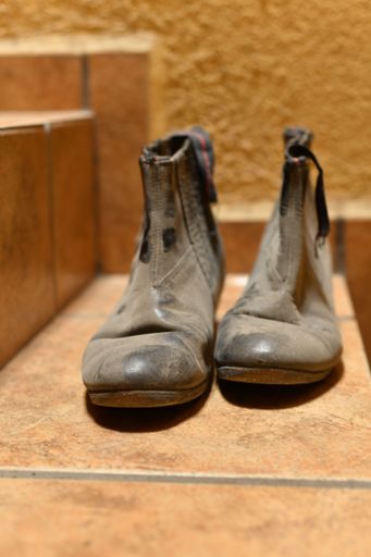 A closeup of a pair of old dirty black shoes on a stair