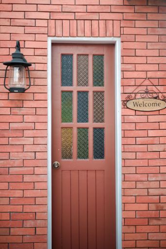 A vertical shot of a brown door with a welcome sign near it
