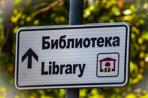A closeup shot of the street sign showing direction toward the library