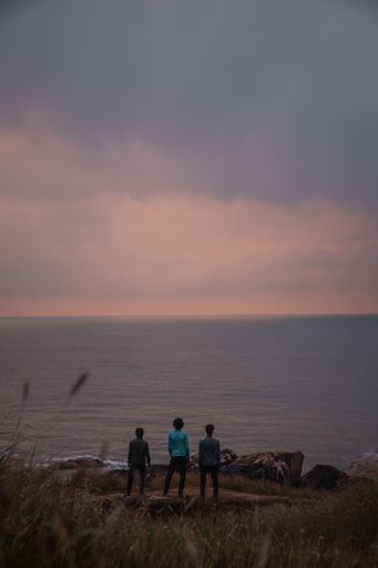 A vertical shot of adults looking at a sunset over a sea