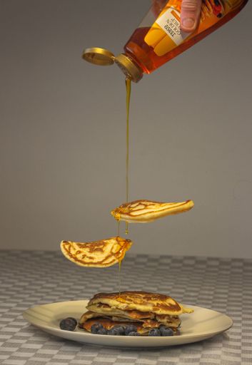 A vertical shot of delicious Tesco golden syrup pouring on pancakes served with blueberries
