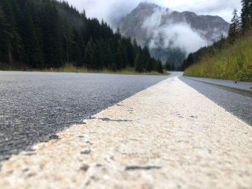 A closeup of a highway to the mountains with trees on both sides