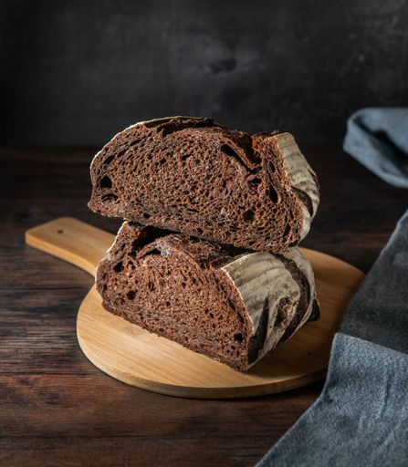 A vertical shot of sliced sourdough bread piles on a circular wooden board