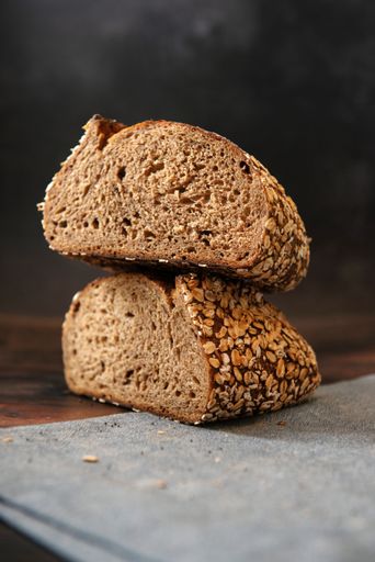 A vertical shot of sliced sourdough bread with whole-grain toppings piles on a tablecloth