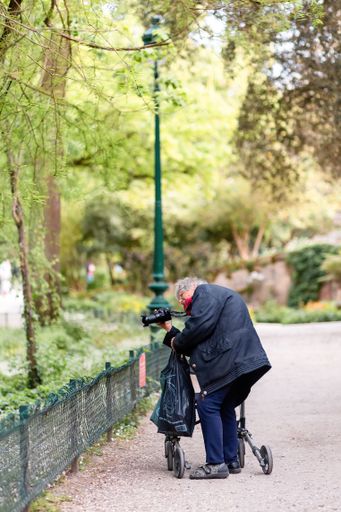 A vertical shot of a woman taking a picture with a camera in the park